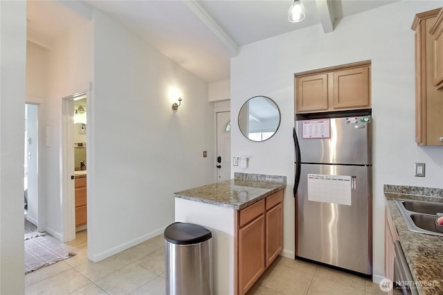 kitchen featuring light tile patterned floors, a sink, baseboards, appliances with stainless steel finishes, and dark stone countertops