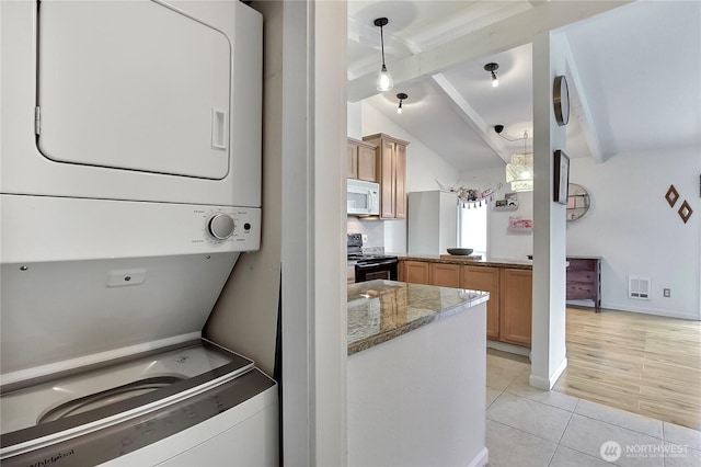 washroom with light tile patterned floors, laundry area, visible vents, baseboards, and stacked washer / drying machine