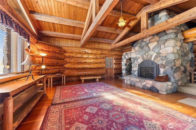 unfurnished living room with vaulted ceiling with beams, a stone fireplace, wood ceiling, and wood finished floors