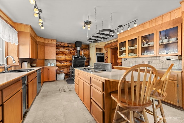 kitchen with wall oven, a kitchen island, light countertops, stainless steel stovetop, and a sink