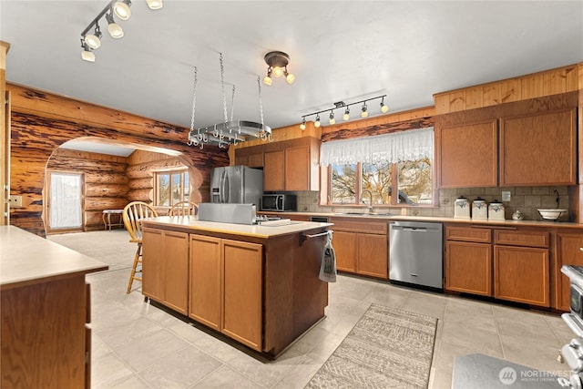 kitchen with appliances with stainless steel finishes, a kitchen island, light countertops, and a sink