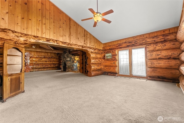 unfurnished living room with rustic walls, carpet floors, high vaulted ceiling, and a ceiling fan