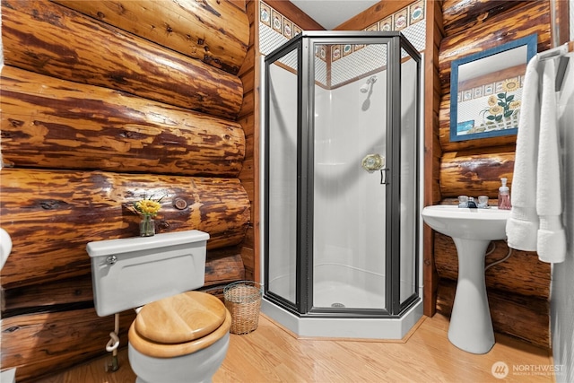 full bathroom featuring toilet, wood finished floors, a stall shower, and log walls