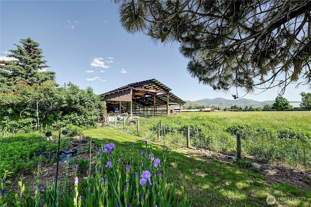 view of yard with an outbuilding, a rural view, a mountain view, and fence