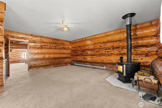 unfurnished living room featuring baseboard heating, a wood stove, ceiling fan, and carpet floors