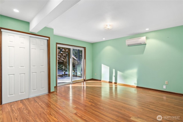 unfurnished bedroom with light wood-type flooring, a wall mounted air conditioner, access to exterior, a closet, and beamed ceiling