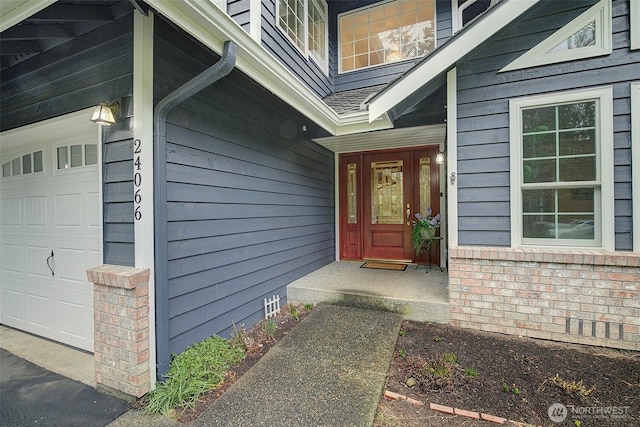 view of exterior entry with a garage, crawl space, and brick siding