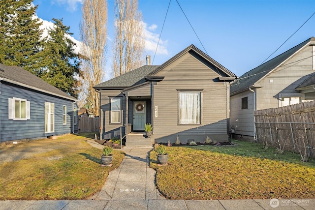 bungalow with a front lawn and fence