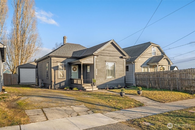 bungalow-style house with a garage, an outbuilding, fence, and driveway