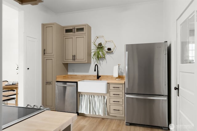 kitchen featuring wood counters, appliances with stainless steel finishes, ornamental molding, light wood-type flooring, and a sink