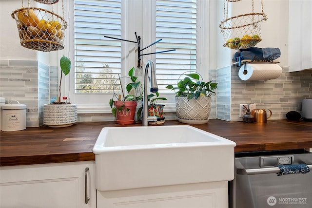 kitchen with a healthy amount of sunlight, white cabinets, butcher block countertops, and decorative backsplash