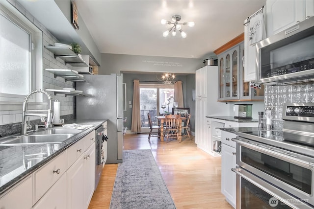 kitchen featuring appliances with stainless steel finishes, sink, white cabinets, a chandelier, and light hardwood / wood-style floors