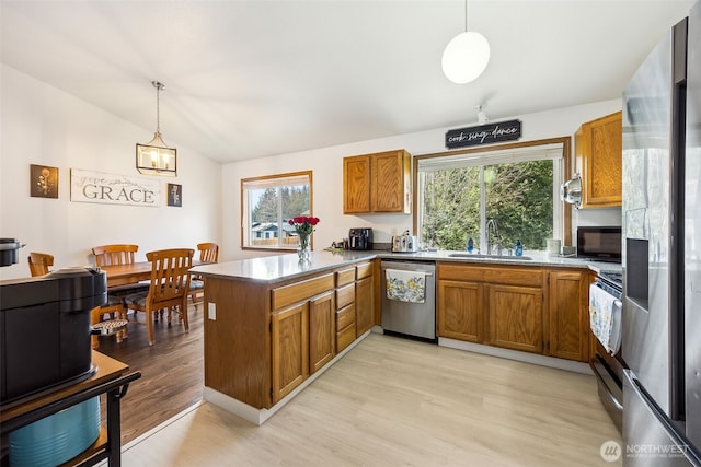 kitchen featuring lofted ceiling, sink, hanging light fixtures, stainless steel appliances, and kitchen peninsula