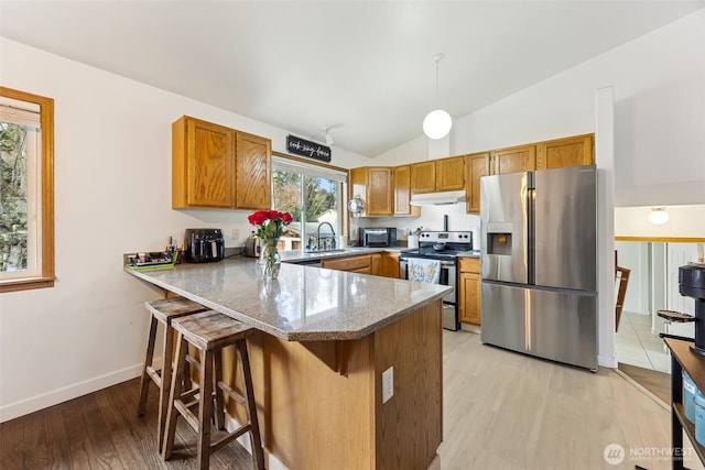 kitchen featuring pendant lighting, lofted ceiling, a breakfast bar area, kitchen peninsula, and stainless steel appliances