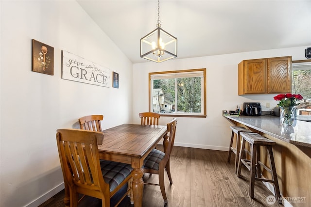 dining space with lofted ceiling, dark hardwood / wood-style flooring, and a notable chandelier