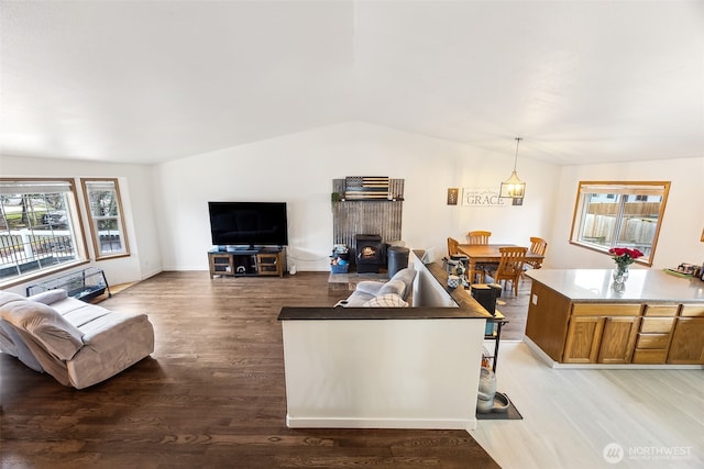 living room with lofted ceiling, a wood stove, and light hardwood / wood-style floors