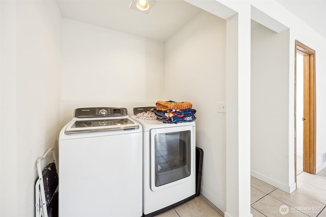 laundry area with washing machine and dryer and light tile patterned floors