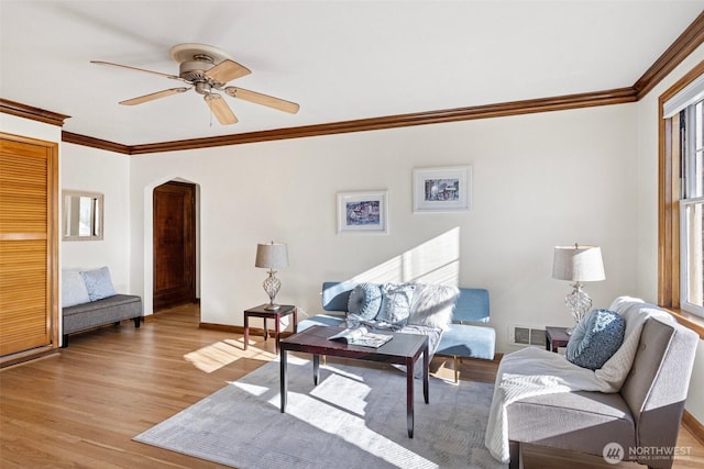 living room featuring light wood-type flooring, ceiling fan, and ornamental molding