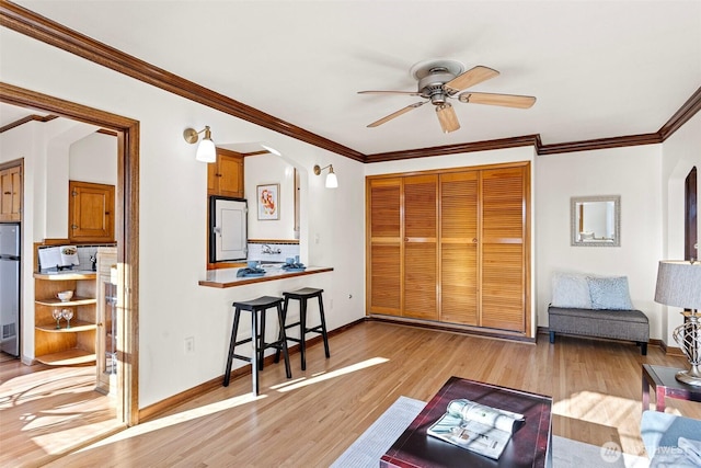 living room featuring light hardwood / wood-style flooring, ceiling fan, and ornamental molding