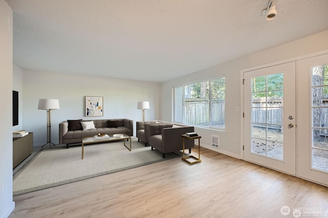 living area featuring visible vents, a textured ceiling, wood finished floors, and french doors