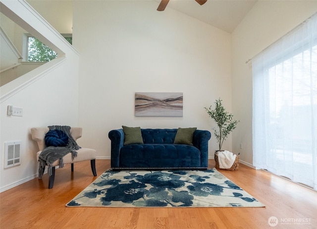 living area featuring hardwood / wood-style flooring, ceiling fan, and high vaulted ceiling