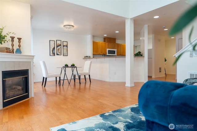 living room featuring a tile fireplace and light wood-type flooring