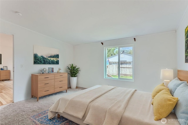 bedroom with ornamental molding and light carpet