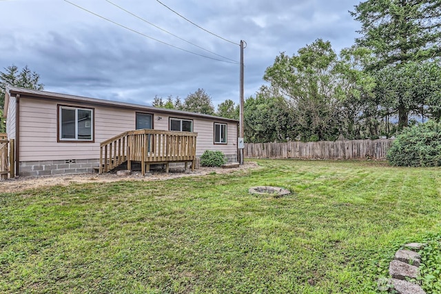 back of house with fence, a deck, and a yard