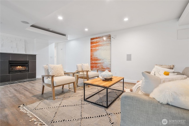 living room featuring a tiled fireplace and light hardwood / wood-style flooring