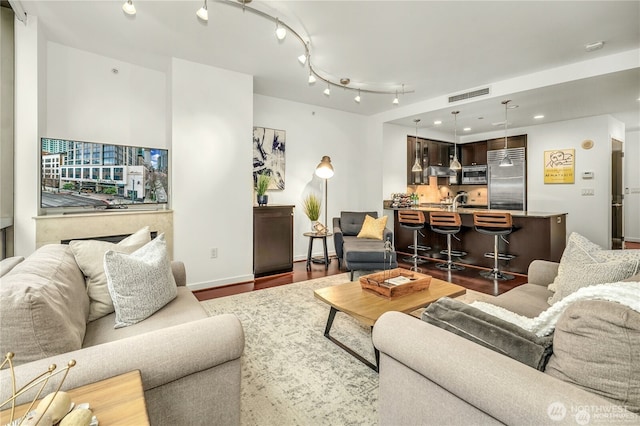 living room featuring dark hardwood / wood-style flooring and track lighting