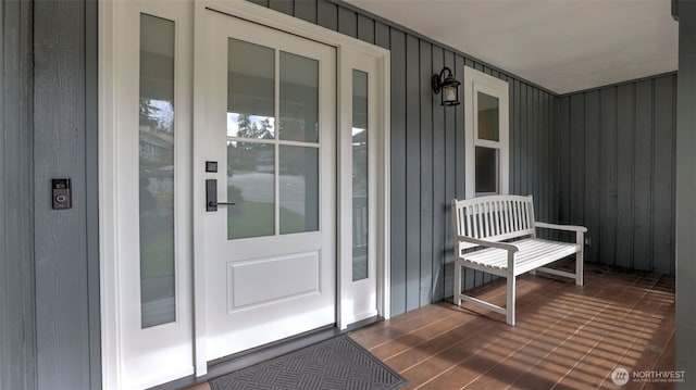 view of exterior entry with board and batten siding and a porch