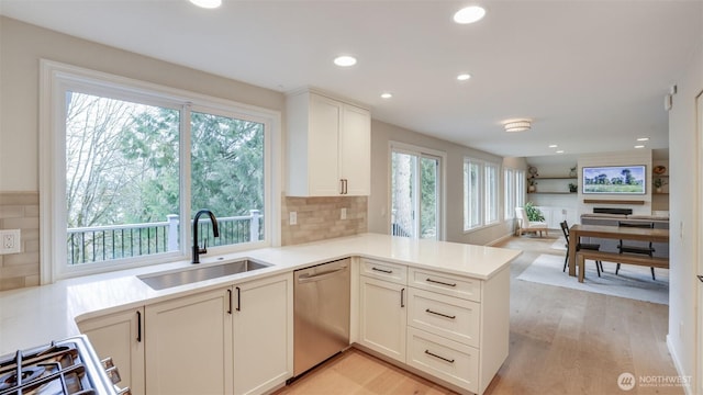 kitchen featuring light countertops, light wood-type flooring, recessed lighting, stainless steel dishwasher, and a sink