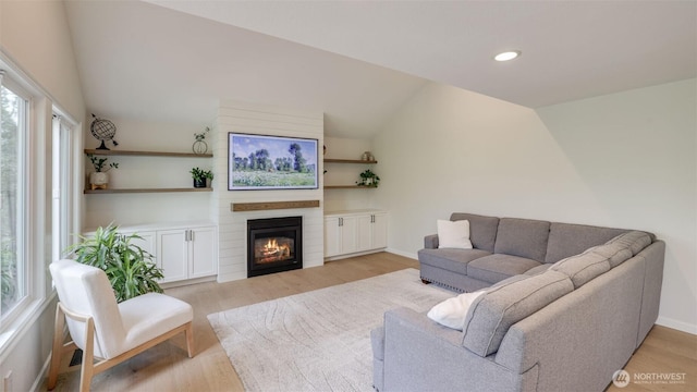 living area featuring baseboards, light wood-style flooring, recessed lighting, vaulted ceiling, and a large fireplace