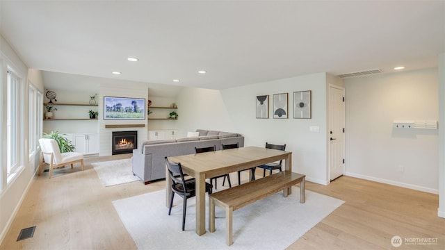 dining room with recessed lighting, visible vents, a lit fireplace, and light wood-style flooring