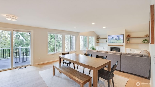 dining area with visible vents, a glass covered fireplace, recessed lighting, light wood finished floors, and baseboards