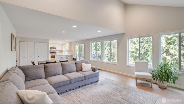 living room featuring recessed lighting, baseboards, and light wood-type flooring