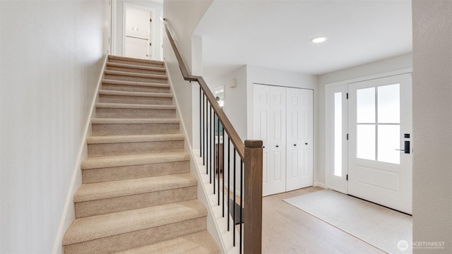 foyer featuring recessed lighting, wood finished floors, and stairs