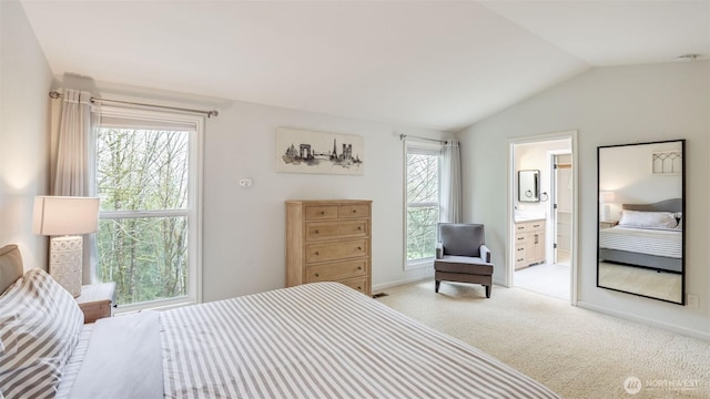 carpeted bedroom featuring baseboards, lofted ceiling, and ensuite bath