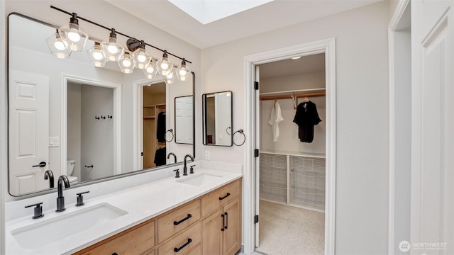 full bathroom featuring double vanity, a spacious closet, toilet, and a sink