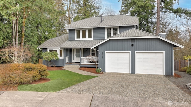 view of front facade with driveway, roof with shingles, covered porch, a chimney, and a garage