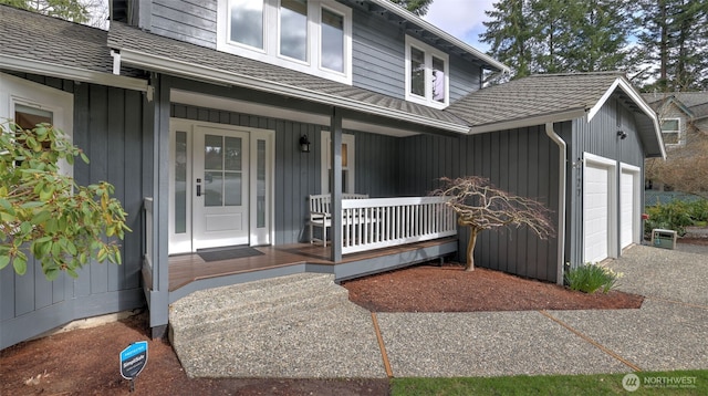 view of exterior entry featuring a porch, an attached garage, board and batten siding, and a shingled roof