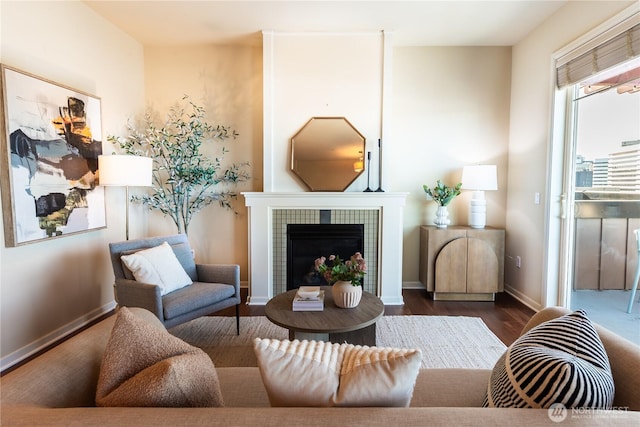 living area featuring dark wood-style floors, baseboards, and a tile fireplace