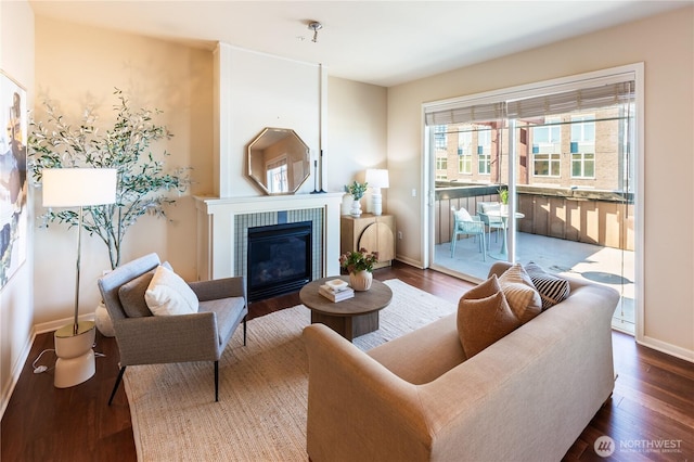 living area with baseboards, a tiled fireplace, and wood finished floors