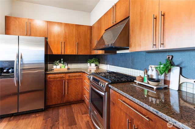 kitchen with stainless steel appliances, tasteful backsplash, under cabinet range hood, and dark wood-style floors