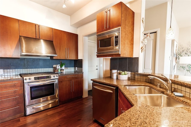 kitchen featuring under cabinet range hood, stainless steel appliances, dark wood-style flooring, a sink, and pendant lighting