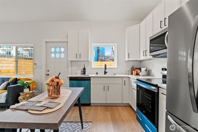 kitchen with light wood-type flooring, stainless steel appliances, sink, and white cabinets