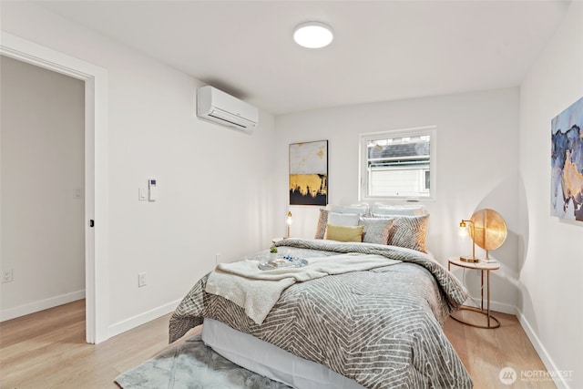 bedroom featuring light hardwood / wood-style floors and an AC wall unit