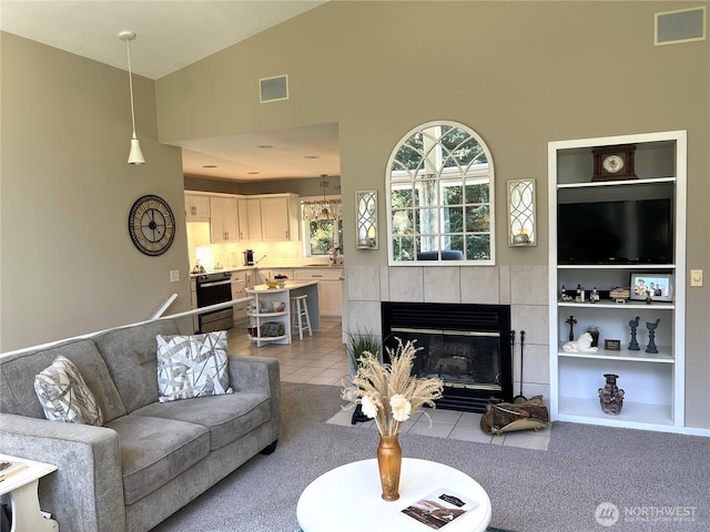 living room with high vaulted ceiling, visible vents, built in features, and a tile fireplace