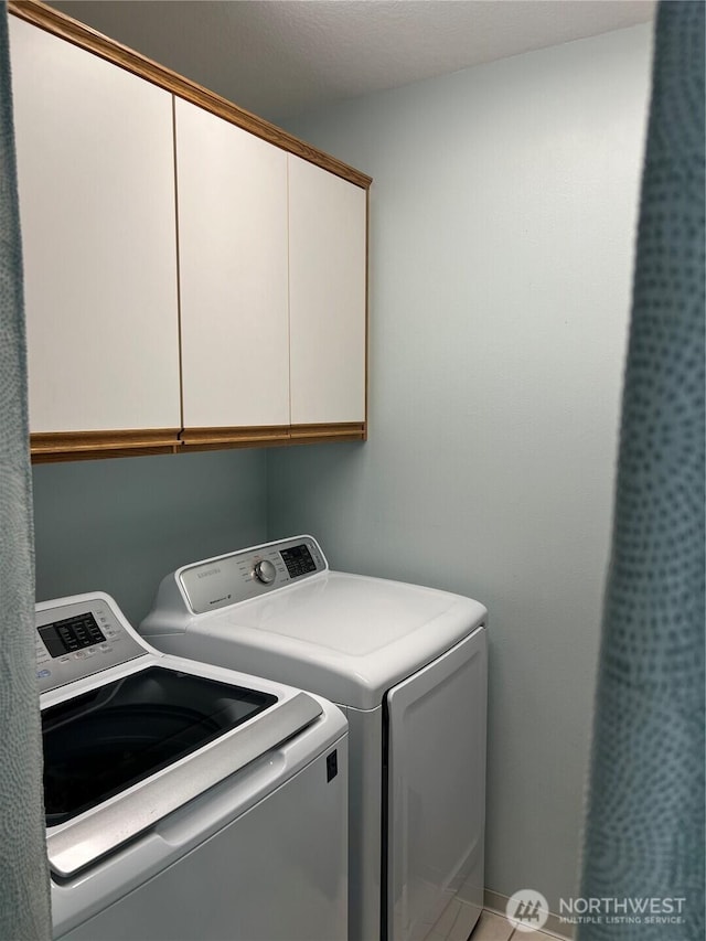 clothes washing area with independent washer and dryer and cabinet space