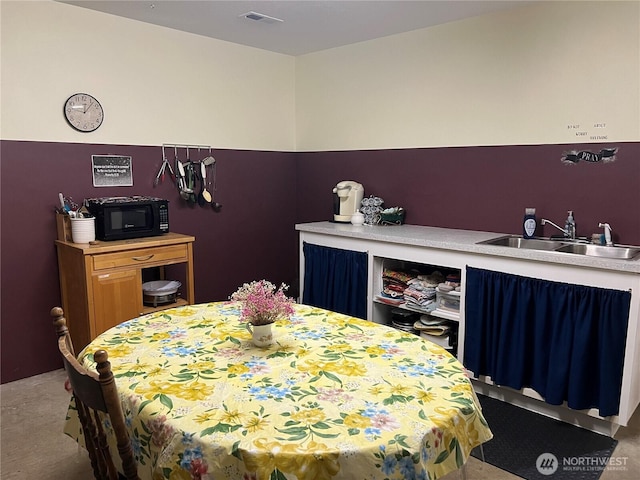 carpeted dining area featuring visible vents and a sink